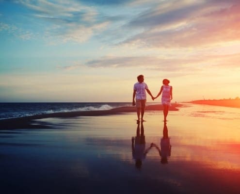 Couples Therapy - Couple on beach walking holding hands.